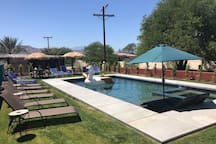 A pool with an umbrella and chairs in the back ground