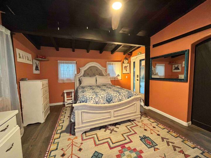 A bedroom with orange walls and white furniture.