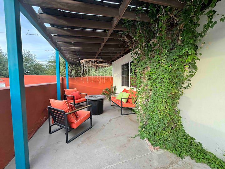 A patio with chairs and tables covered in vines.