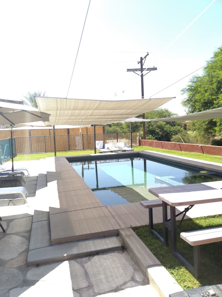 A pool with benches and umbrellas in the background.