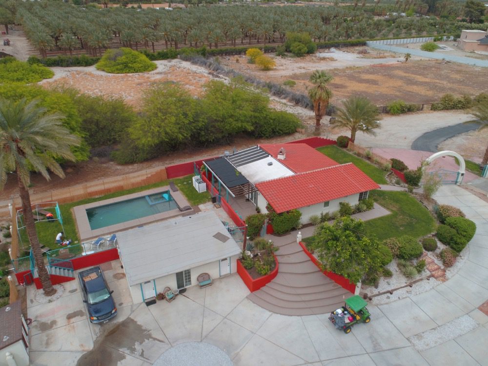 A large red house with a pool and a lot of trees
